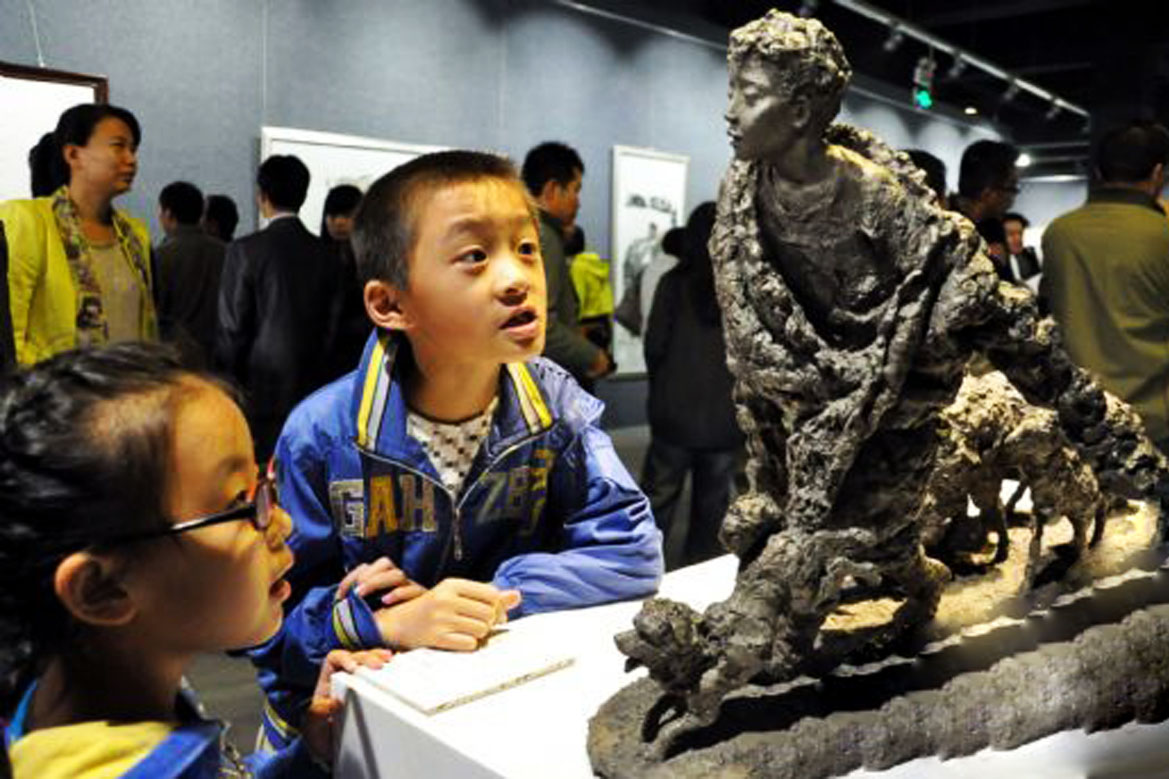 小孩在參觀胡學富雕塑個人展覽當中的放羊的少年雕塑作品